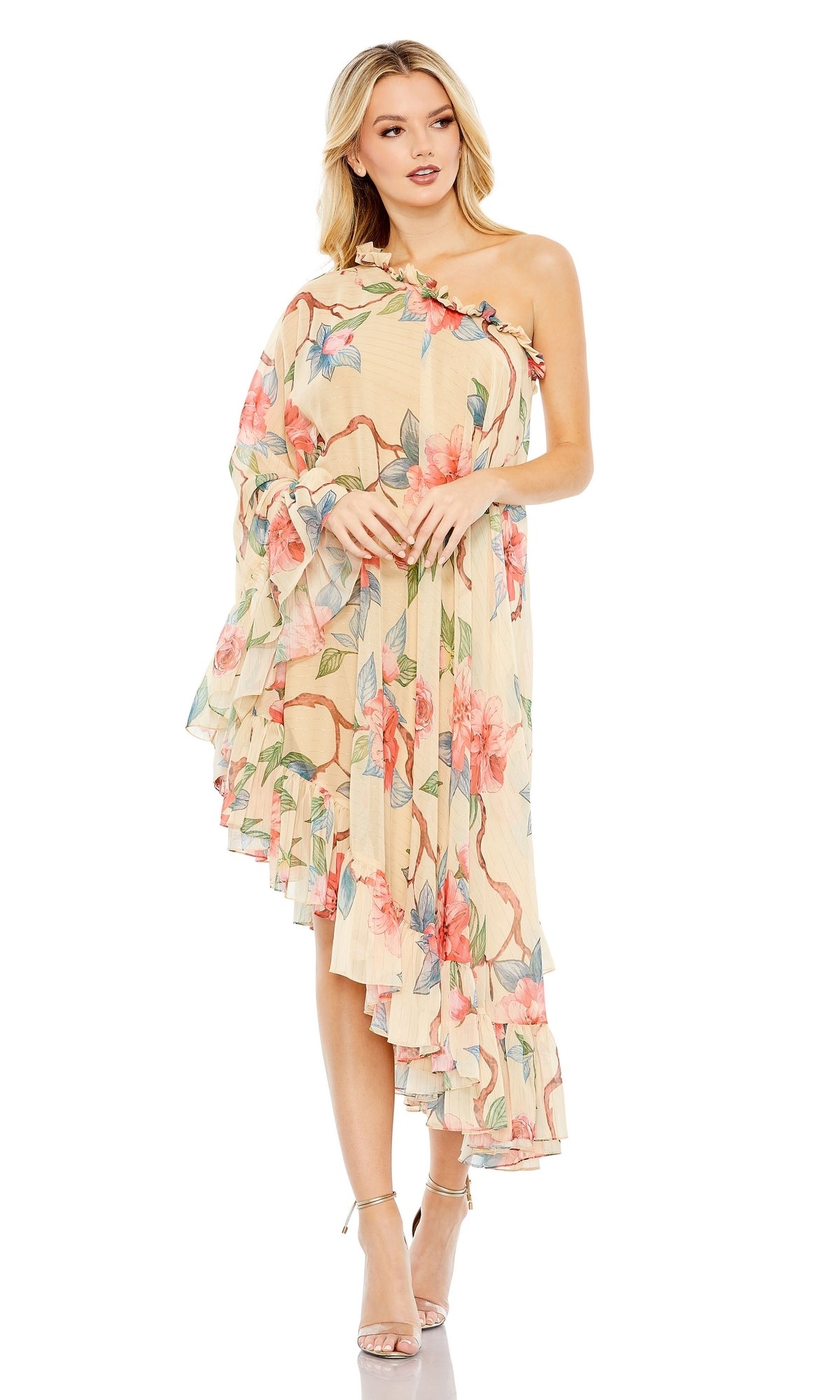 A woman wears the Long Formal Dress 55830 by Mac Duggal, a beige one-shoulder gown with a floral print and ruffled hem, styled with strappy high heels.